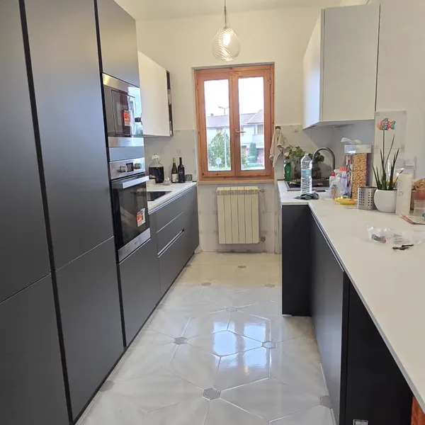 Cucina antracite con colonna forno e finestra in fondo