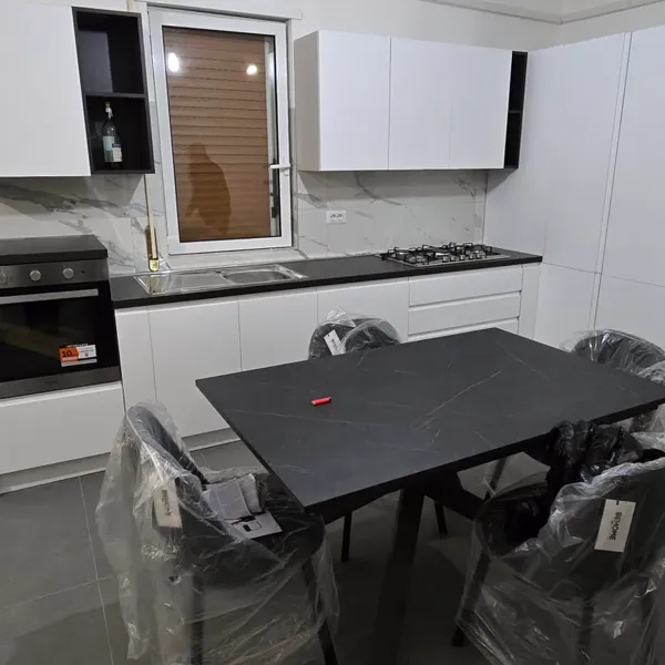 Cucina lineare bianca con boiserie marmo e tavolo nero