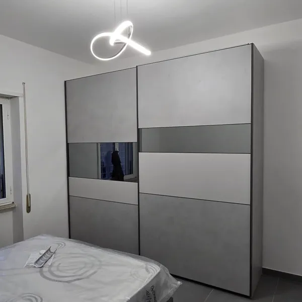 Armadio scorrevole grigio con letto matrimoniale moderno